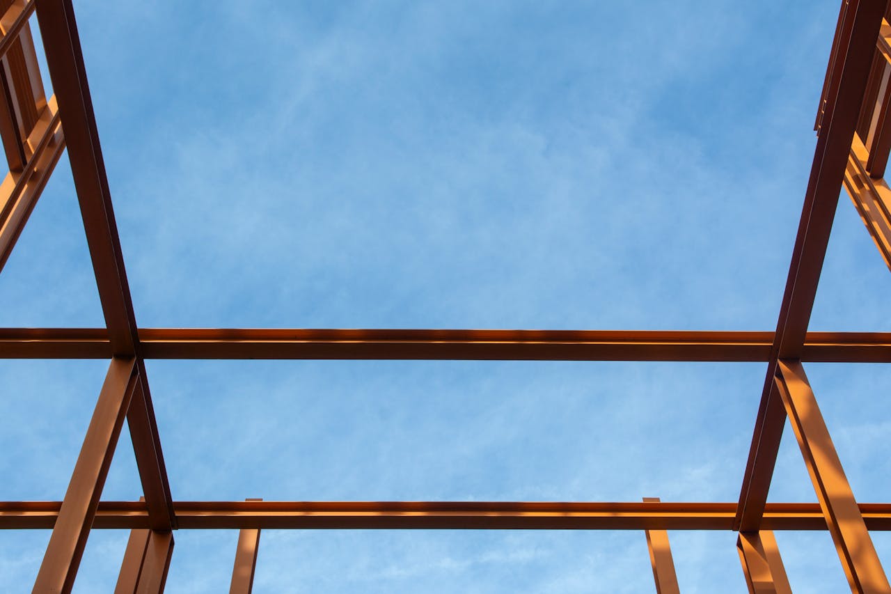 hero-img-02 Silhouette of a metal framework against a bright blue sky, captured from below.