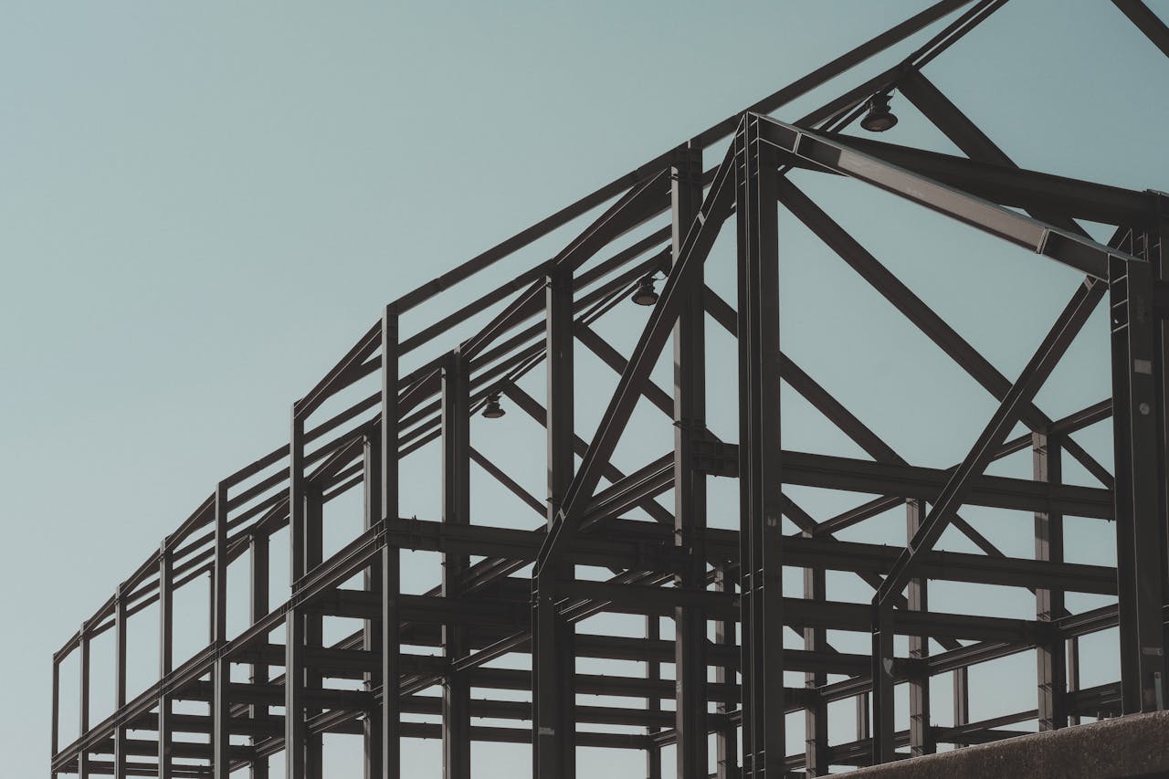 contact-img Modern steel framework structure under clear sky, showcasing architectural design.